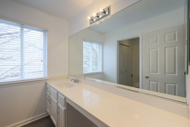 bathroom featuring toilet, vanity, and a healthy amount of sunlight