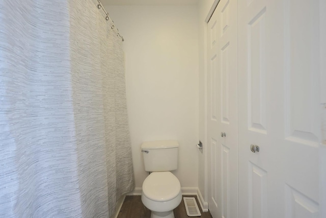 bathroom with toilet, a shower with curtain, visible vents, and baseboards