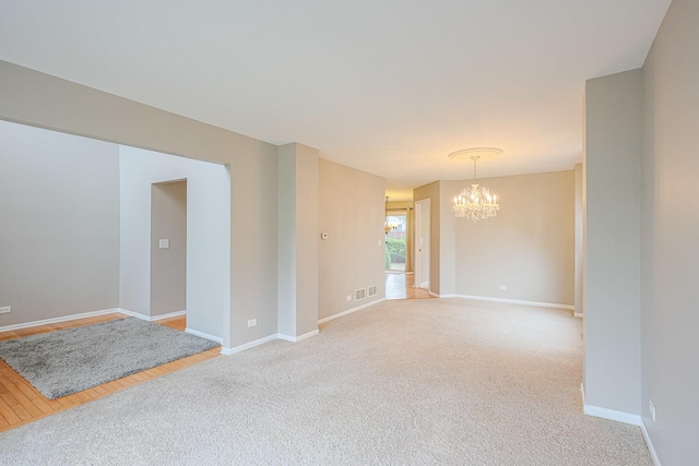 unfurnished room featuring a chandelier, baseboards, visible vents, and light carpet