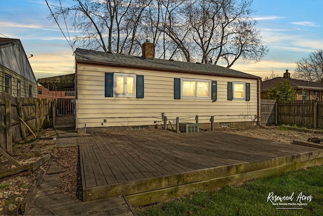 511 N Cleveland Ave, Bradley, IL 60915 - back of house at dusk with a chimney, a wooden deck, and a fenced backyard