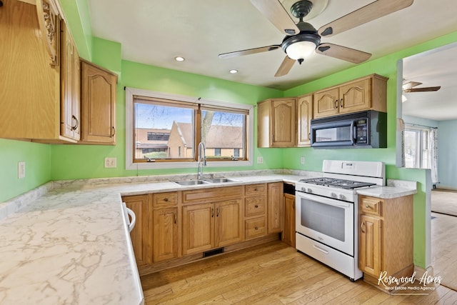 511 N Cleveland Ave, Bradley, IL 60915 - kitchen featuring white gas range, a sink, black microwave, light wood-style flooring, and ceiling fan