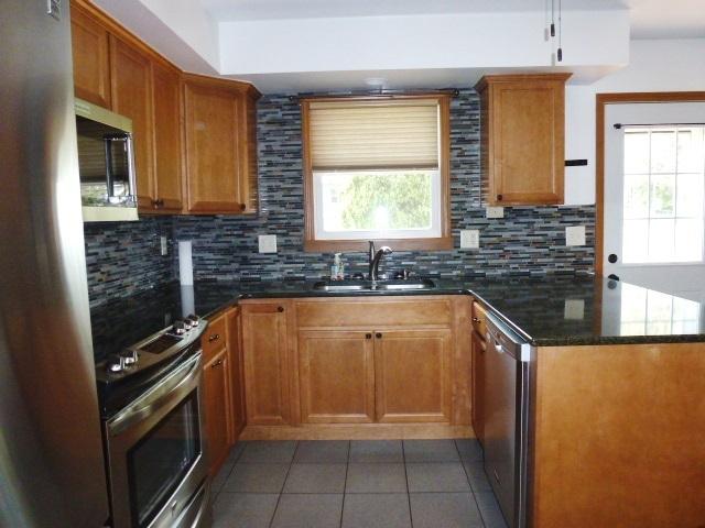 1026 State Route 10 E, Clinton, IL 61727 - kitchen featuring appliances with stainless steel finishes, light tile patterned floors, decorative backsplash, and a sink