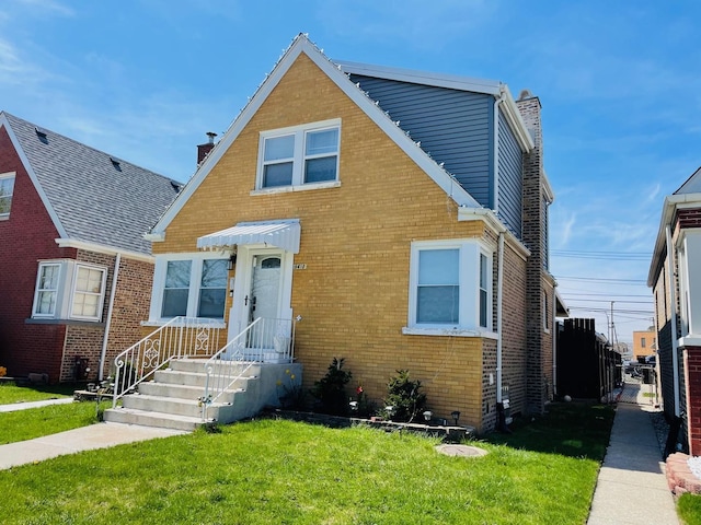bungalow-style house with brick siding, a chimney, and a front lawn