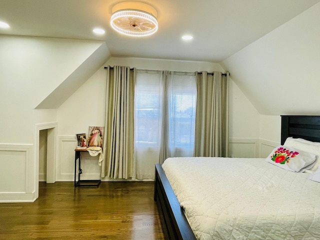 bedroom featuring a decorative wall, a wainscoted wall, vaulted ceiling, and dark wood-type flooring