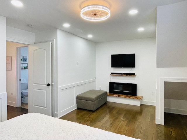 bedroom featuring recessed lighting, a glass covered fireplace, and wood finished floors