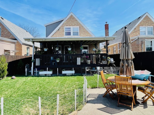 rear view of house featuring a yard, brick siding, fence, and a wooden deck