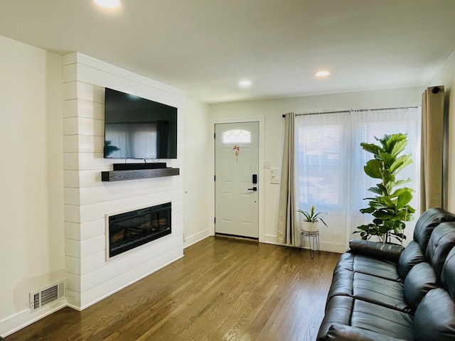 living area with visible vents, dark wood-style flooring, baseboards, recessed lighting, and a large fireplace