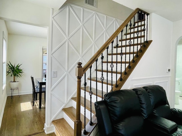 stairway featuring arched walkways, visible vents, and wood finished floors