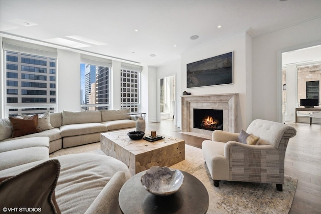 living room featuring wood finished floors, a fireplace, recessed lighting, and crown molding