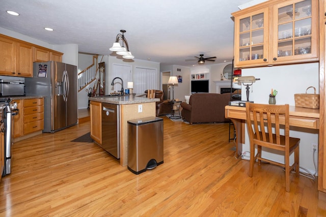 kitchen with light wood-style flooring, a sink, stainless steel appliances, a kitchen island with sink, and ceiling fan