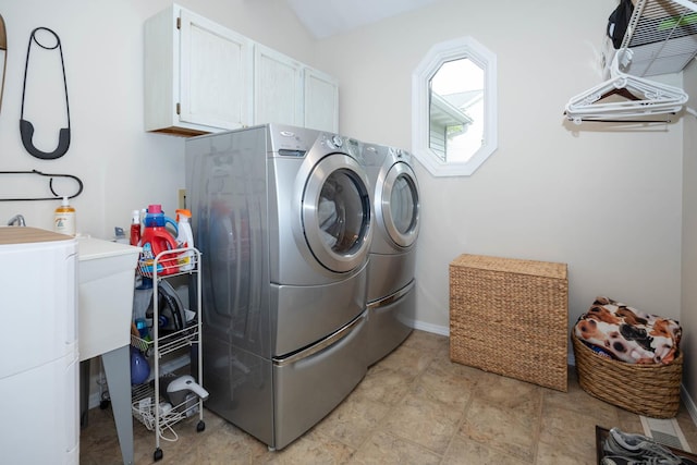 laundry area with washing machine and clothes dryer, stone finish flooring, and cabinet space
