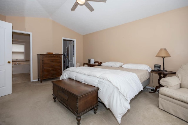 bedroom featuring vaulted ceiling, light colored carpet, ensuite bathroom, and ceiling fan