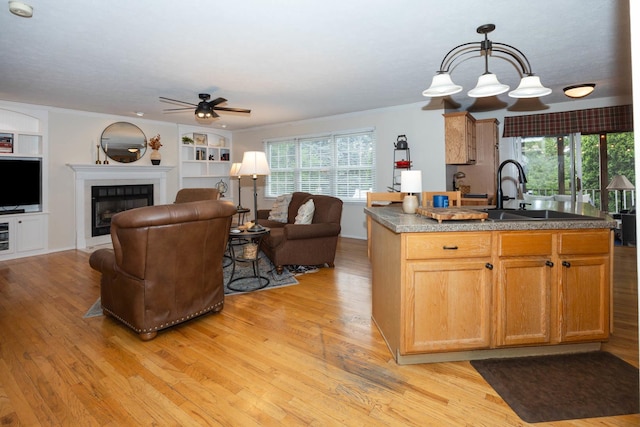 kitchen featuring light wood-style flooring, open floor plan, ceiling fan, and a sink