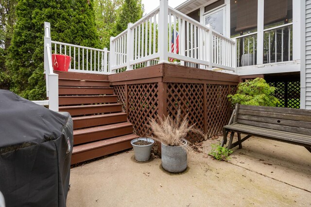 wooden deck with area for grilling, a patio, and stairs