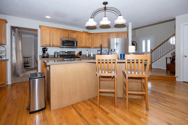 kitchen with a breakfast bar, light wood-type flooring, recessed lighting, pendant lighting, and appliances with stainless steel finishes