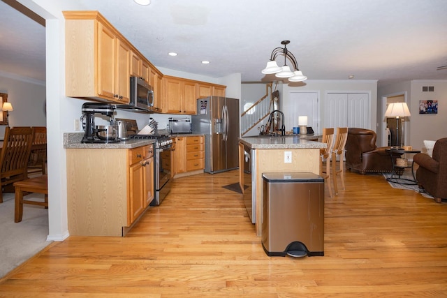 kitchen with ornamental molding, light wood-style floors, open floor plan, a center island with sink, and stainless steel appliances
