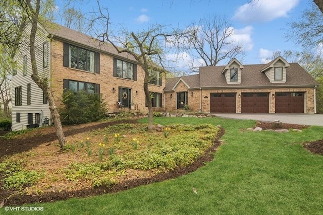 colonial-style house featuring brick siding, a garage, driveway, and a front lawn