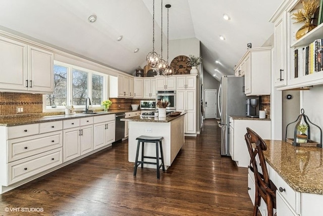kitchen with a sink, appliances with stainless steel finishes, decorative backsplash, and a center island