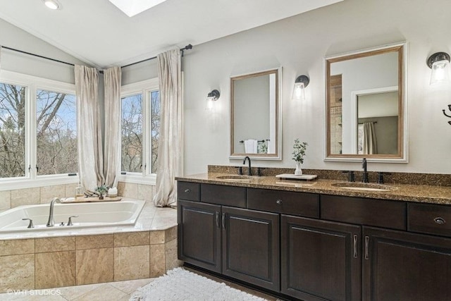 bathroom with double vanity, vaulted ceiling, a sink, and a bath
