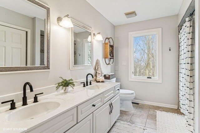 full bathroom featuring a sink, baseboards, toilet, and double vanity