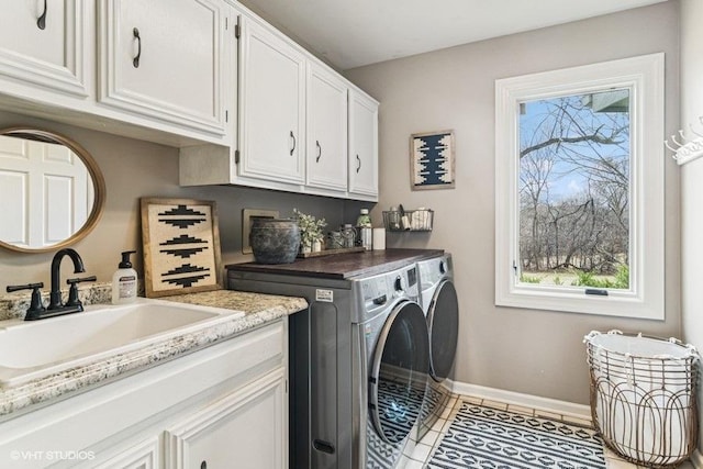 washroom with washing machine and clothes dryer, cabinet space, a sink, tile patterned floors, and baseboards