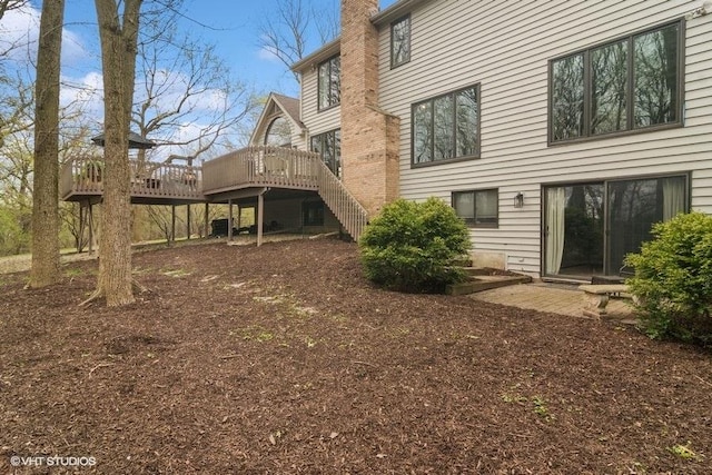 rear view of property with stairs, a chimney, and a deck