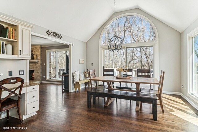 dining space featuring high vaulted ceiling, a chandelier, dark wood-style floors, and a fireplace