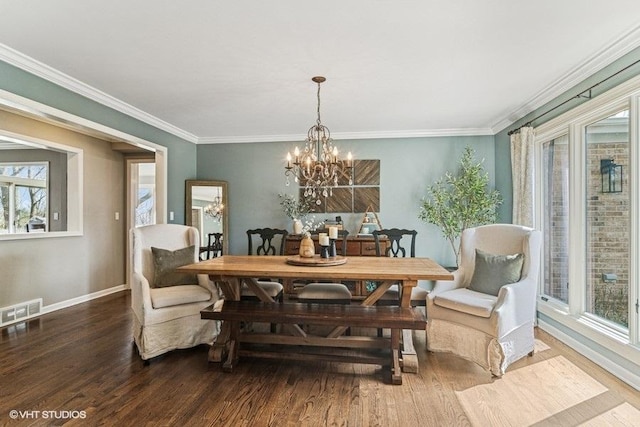 dining area with crown molding, an inviting chandelier, baseboards, wood finished floors, and visible vents