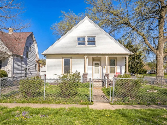 bungalow-style home featuring a gate, a porch, a front lawn, and a fenced front yard