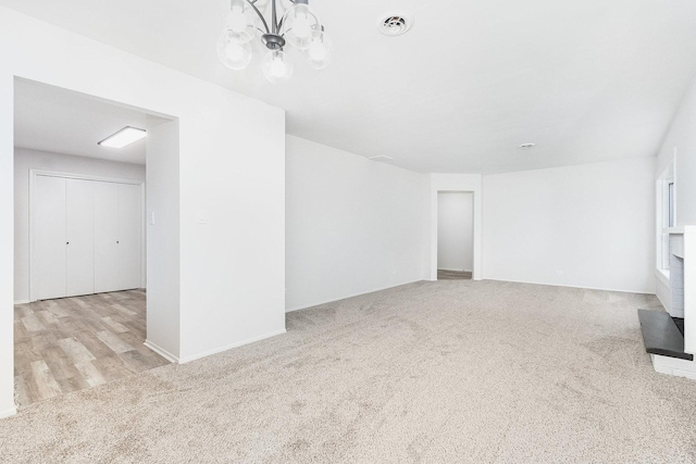 unfurnished living room featuring visible vents, carpet flooring, and a notable chandelier