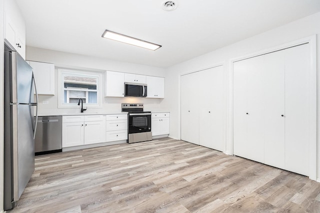 kitchen featuring light wood finished floors, light countertops, white cabinets, and appliances with stainless steel finishes