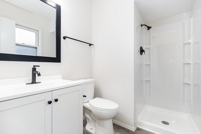 bathroom featuring a shower stall, toilet, vanity, and wood finished floors