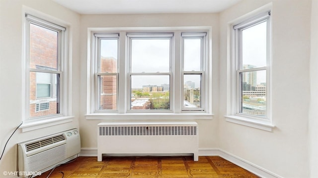 interior space with radiator heating unit, a wall unit AC, and plenty of natural light