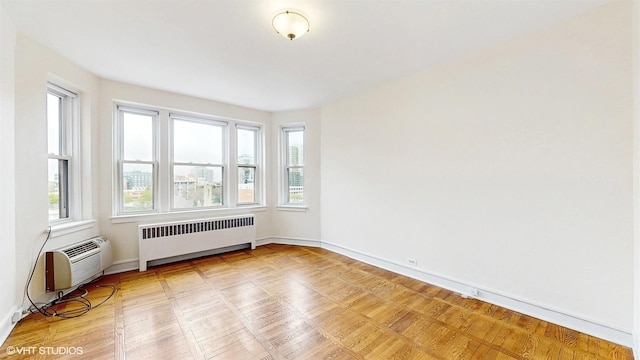 unfurnished room featuring a wall mounted AC, baseboards, and radiator heating unit