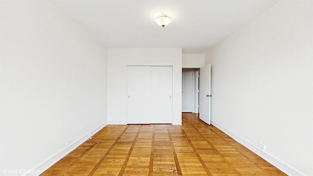 unfurnished bedroom featuring baseboards, light wood finished floors, and a closet