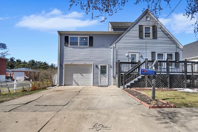 view of front of home with a garage, concrete driveway, fence, and a deck