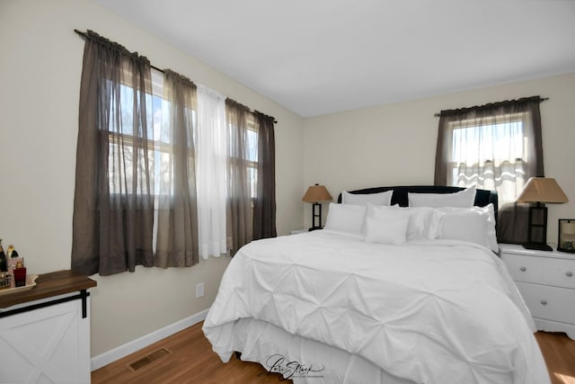 bedroom featuring baseboards, wood finished floors, and visible vents