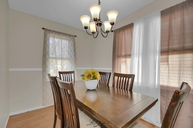 dining room featuring a chandelier, light wood-type flooring, and baseboards
