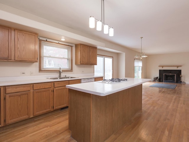 kitchen with a sink, white appliances, a wealth of natural light, light wood finished floors, and light countertops