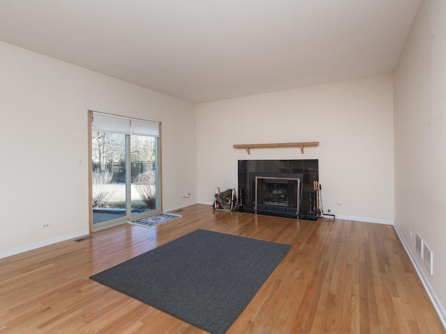 unfurnished living room featuring a fireplace, wood finished floors, visible vents, and baseboards