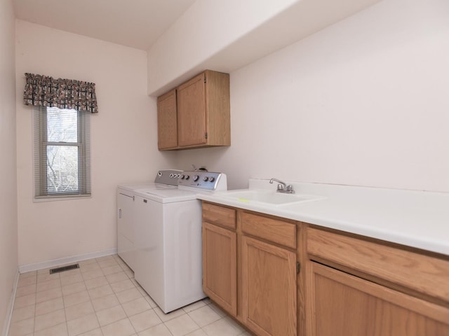 clothes washing area with washing machine and clothes dryer, a sink, light tile patterned flooring, visible vents, and cabinet space