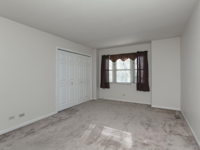 unfurnished bedroom with carpet, a closet, baseboards, and visible vents