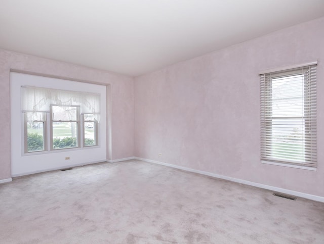 empty room with plenty of natural light, visible vents, and carpet