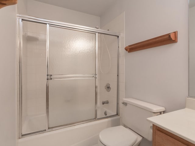 full bath with vanity, shower / bath combination with glass door, and toilet