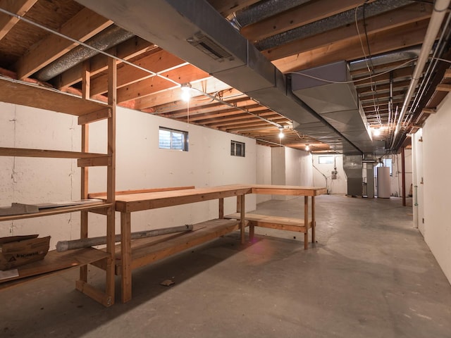 basement with visible vents, gas water heater, and heating unit