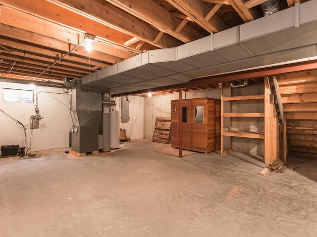 unfinished below grade area featuring electric panel, heating unit, and water heater