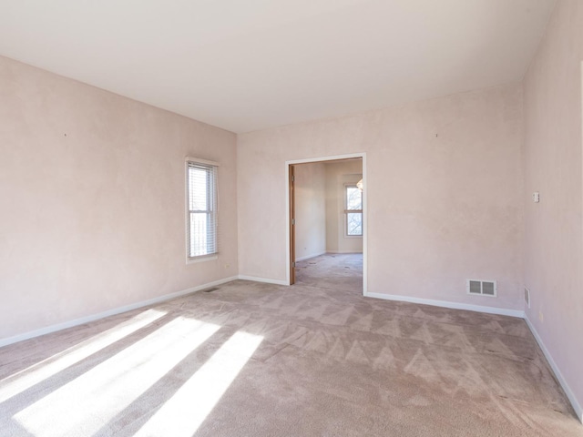empty room featuring light colored carpet, baseboards, and visible vents