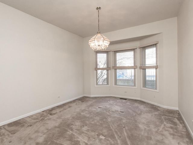 empty room with carpet, visible vents, baseboards, and a notable chandelier