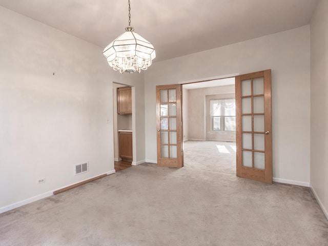 unfurnished dining area featuring light colored carpet, a notable chandelier, french doors, and visible vents