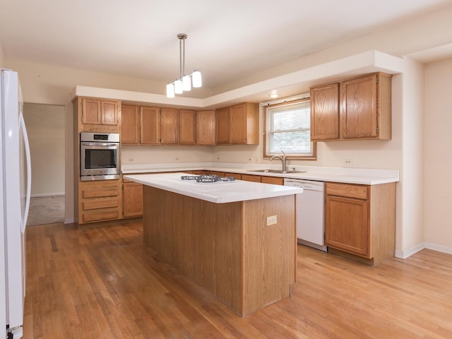kitchen featuring light countertops, a sink, white appliances, light wood-type flooring, and a kitchen island